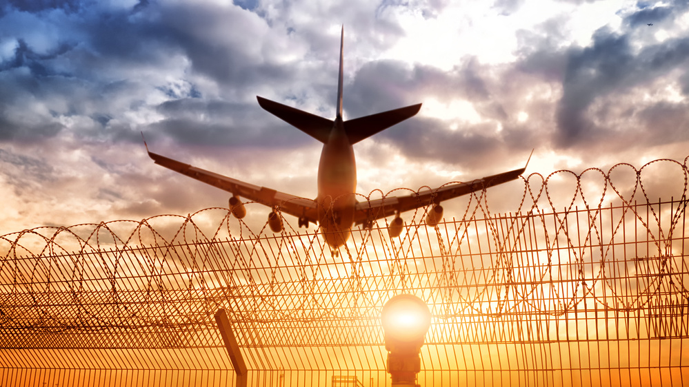 modern airplane landing to airport runway on beautiful sunset sky background with approach lights and airfield border wire fence passenger aircraft flying air travel landscape panorama view